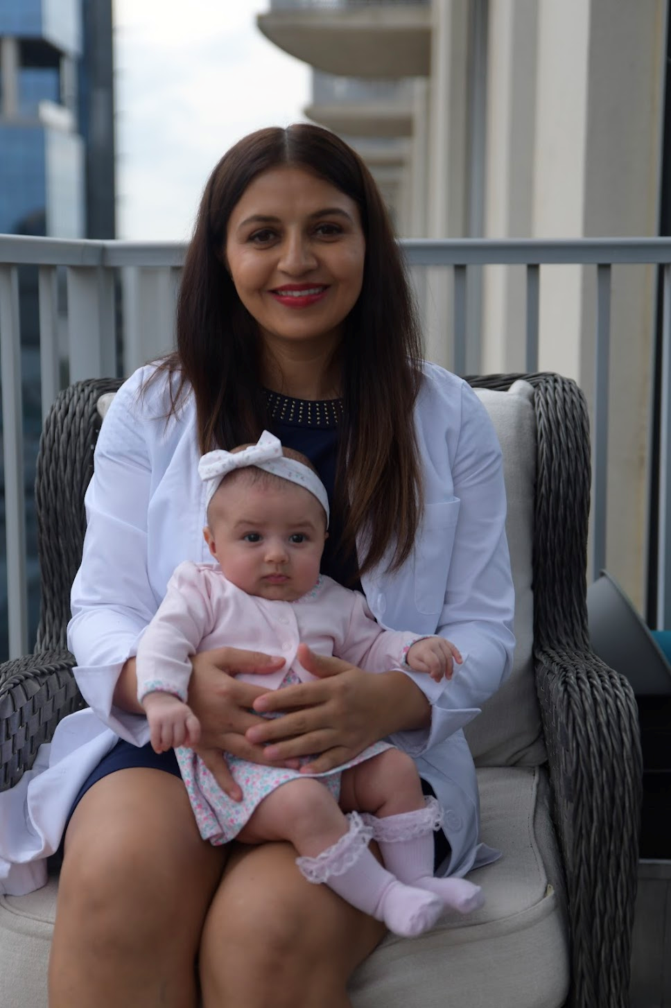 A female Doctor in white apron is with baby girl sitting on sofa